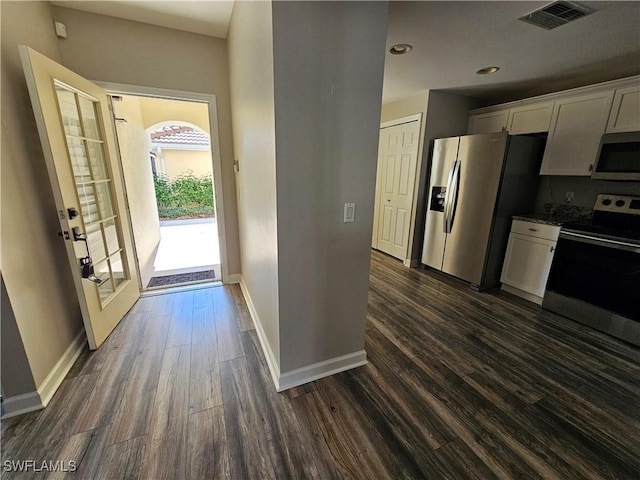 kitchen featuring white cabinetry, appliances with stainless steel finishes, dark hardwood / wood-style floors, and light stone counters