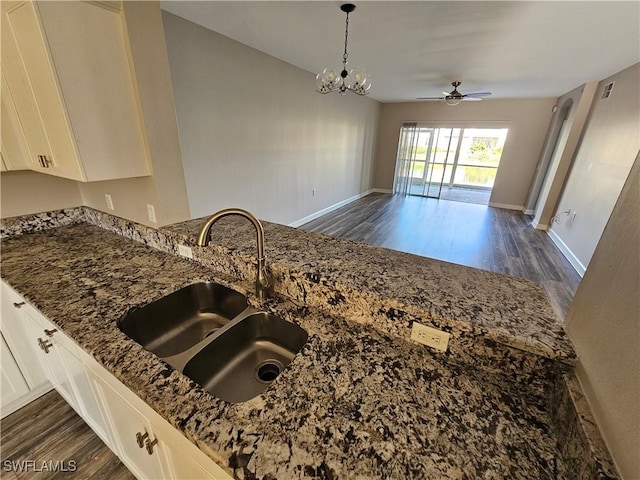 kitchen with pendant lighting, white cabinetry, sink, dark stone countertops, and dark hardwood / wood-style flooring