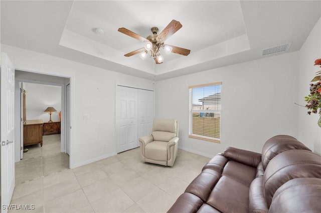 living area featuring light tile patterned floors, a raised ceiling, and ceiling fan