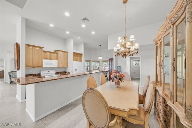 tiled dining room featuring a chandelier, a towering ceiling, and sink