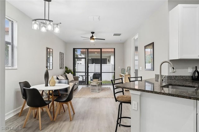 dining space featuring light wood-type flooring, ceiling fan, and sink