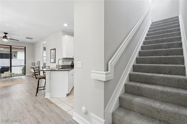 staircase featuring wood-type flooring, ceiling fan, and sink