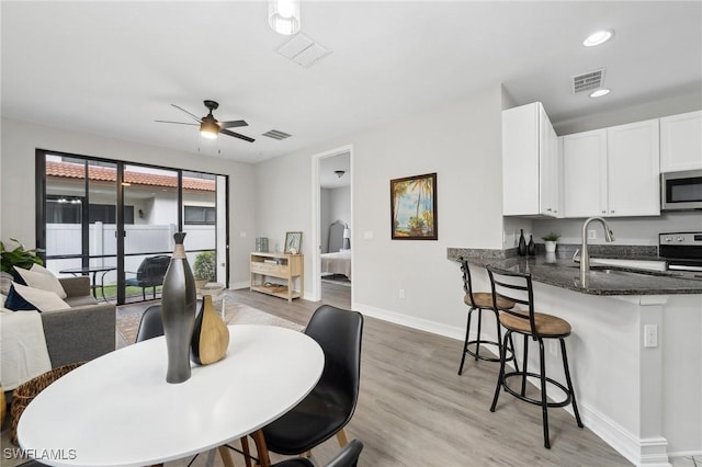 dining room with ceiling fan, sink, and light hardwood / wood-style flooring