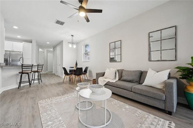 living room featuring ceiling fan and light hardwood / wood-style flooring