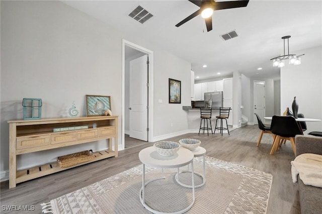 living room featuring wood-type flooring and ceiling fan with notable chandelier