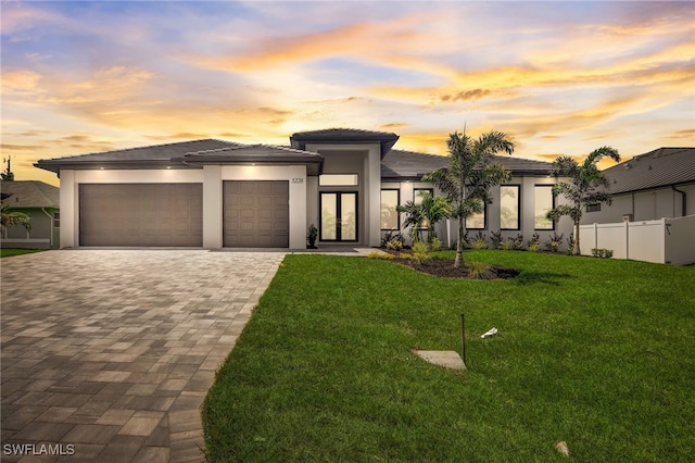 prairie-style house featuring french doors, a garage, and a lawn