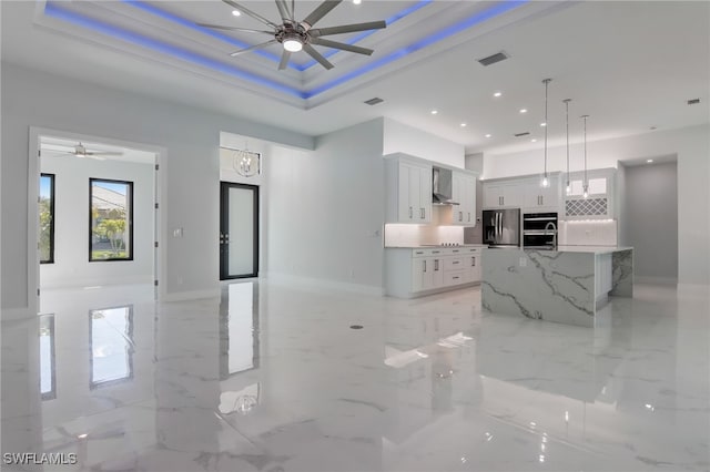 kitchen featuring appliances with stainless steel finishes, white cabinetry, a raised ceiling, and a spacious island