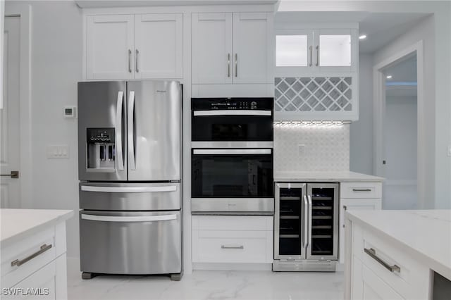 kitchen with appliances with stainless steel finishes, backsplash, white cabinetry, and wine cooler