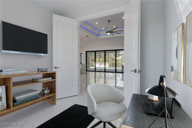 home office with a tray ceiling and ceiling fan