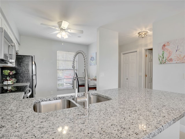 kitchen with light stone countertops, white cabinets, sink, kitchen peninsula, and ceiling fan