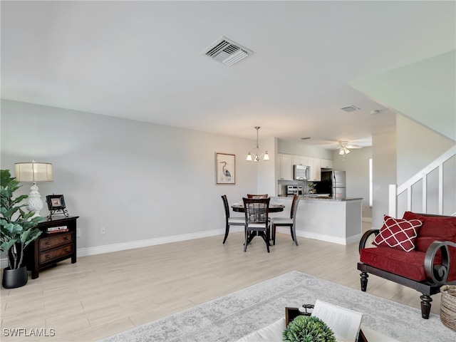 living room featuring light wood-type flooring and ceiling fan with notable chandelier