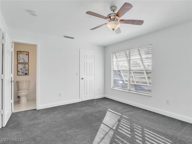 unfurnished bedroom with ceiling fan, dark carpet, ensuite bathroom, and a closet