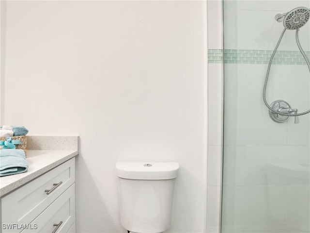 bathroom with tiled shower, toilet, and vanity