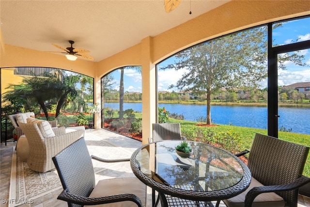 sunroom / solarium featuring ceiling fan and a water view