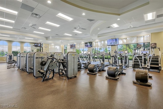 gym with ceiling fan, a drop ceiling, a tray ceiling, and ornamental molding