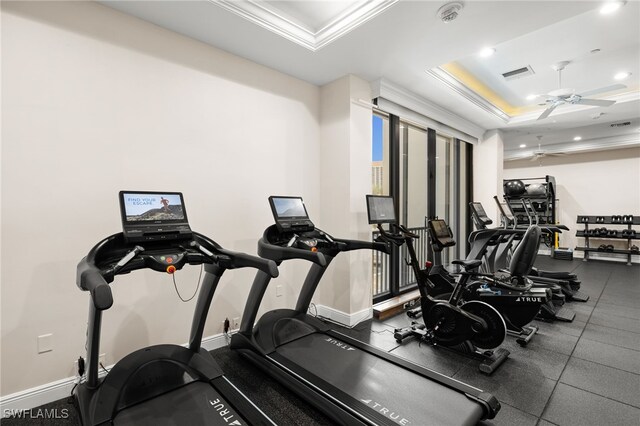 exercise room with a ceiling fan, visible vents, crown molding, baseboards, and a tray ceiling