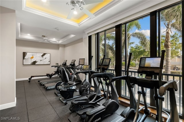 workout area with a raised ceiling, ceiling fan, and ornamental molding