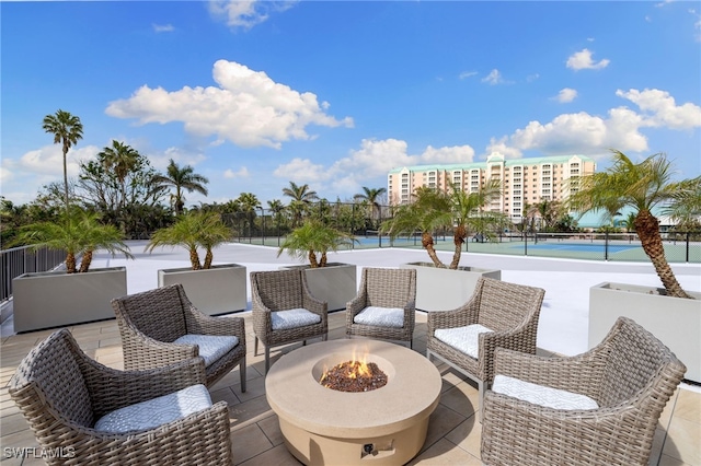 view of patio / terrace with fence, a tennis court, and a fire pit