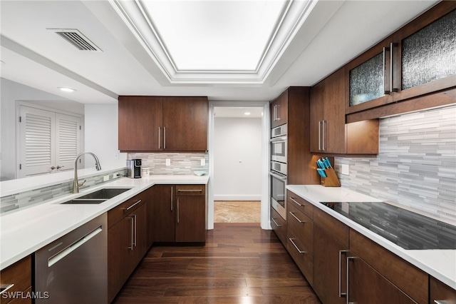 kitchen with dark brown cabinetry, sink, stainless steel appliances, dark hardwood / wood-style floors, and backsplash