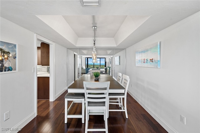 dining room with dark hardwood / wood-style floors and a tray ceiling