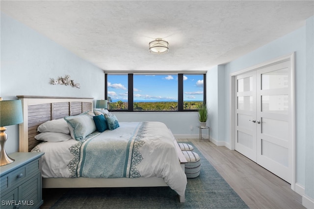 bedroom with light wood-type flooring, a textured ceiling, and a closet