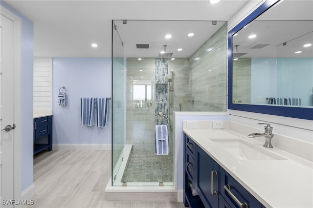 bathroom with hardwood / wood-style floors, vanity, and a shower with shower door