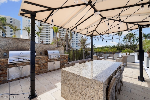 view of patio featuring an outdoor kitchen, an outdoor bar, a gazebo, and a grill