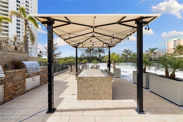 view of patio / terrace featuring grilling area, a water view, and exterior kitchen