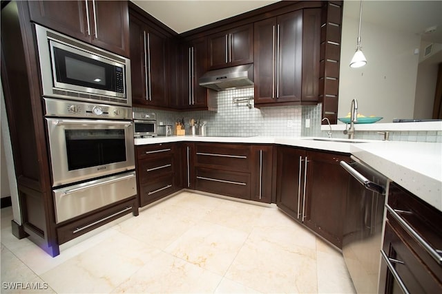 kitchen featuring appliances with stainless steel finishes, tasteful backsplash, hanging light fixtures, and sink