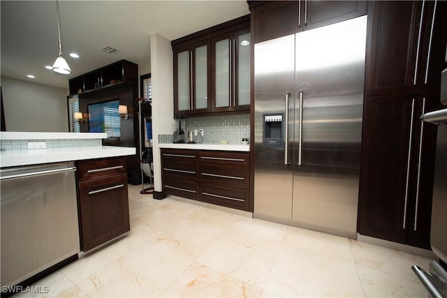 kitchen with decorative backsplash, pendant lighting, stainless steel appliances, and dark brown cabinets