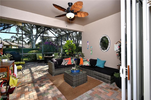 view of patio with ceiling fan, an outdoor living space, and glass enclosure