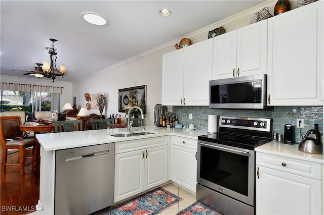 kitchen featuring appliances with stainless steel finishes, pendant lighting, sink, white cabinets, and kitchen peninsula