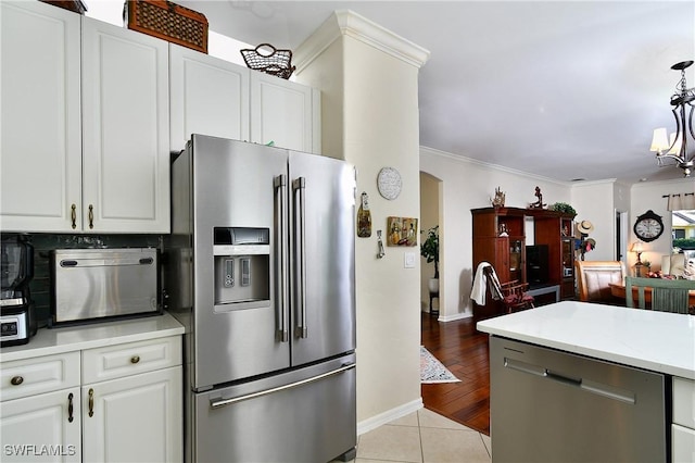 kitchen featuring hanging light fixtures, white cabinetry, appliances with stainless steel finishes, and crown molding