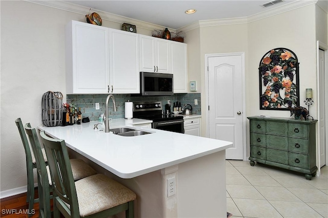 kitchen with a breakfast bar, white cabinetry, sink, kitchen peninsula, and stainless steel appliances