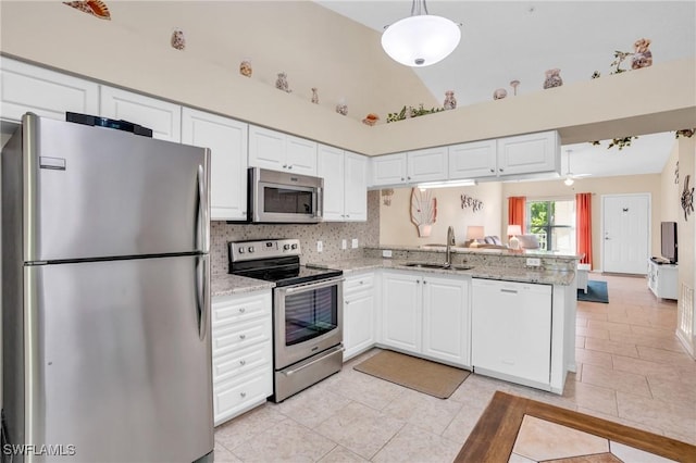 kitchen with kitchen peninsula, appliances with stainless steel finishes, sink, white cabinets, and light tile patterned flooring