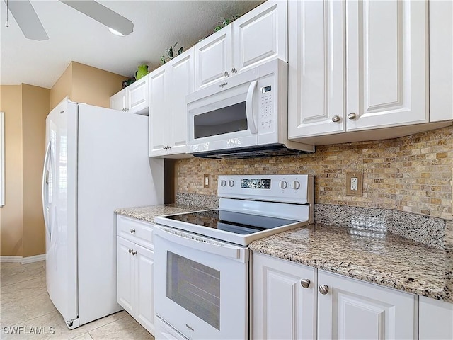 kitchen with light stone counters, light tile patterned floors, white cabinets, and white appliances