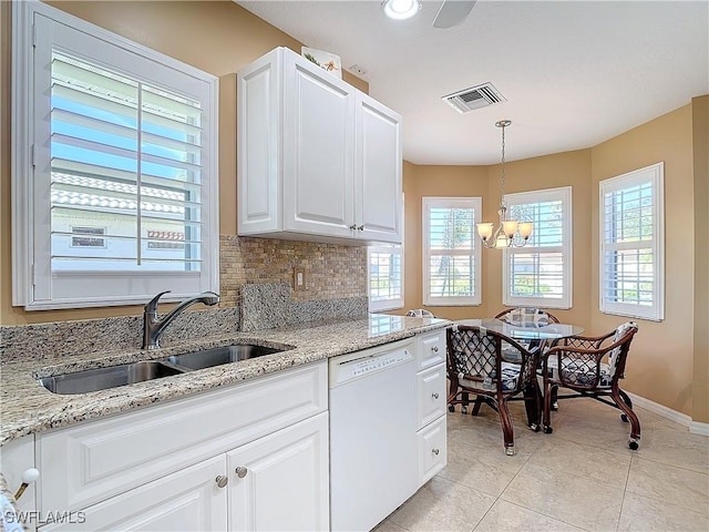 kitchen with light stone counters, white dishwasher, sink, pendant lighting, and white cabinetry