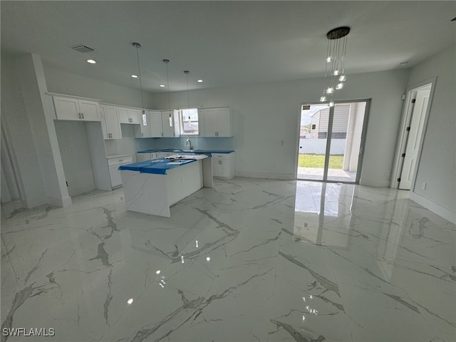 kitchen featuring a kitchen island, sink, white cabinetry, and hanging light fixtures