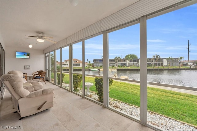 sunroom featuring ceiling fan and a water view