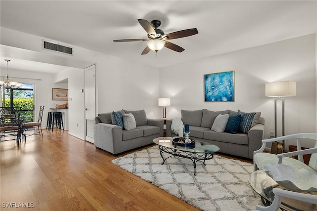 living room with ceiling fan with notable chandelier and hardwood / wood-style flooring