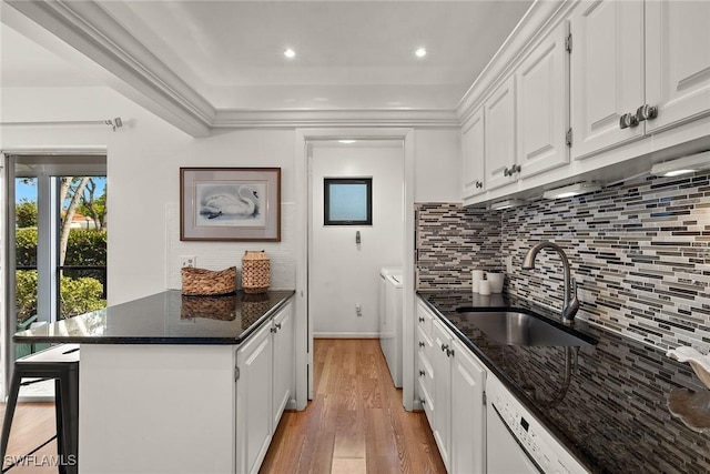 kitchen featuring washer and clothes dryer, dark stone countertops, white cabinetry, and sink