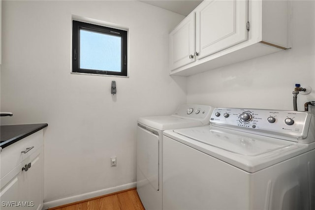 washroom with washer and clothes dryer, cabinets, and light hardwood / wood-style flooring