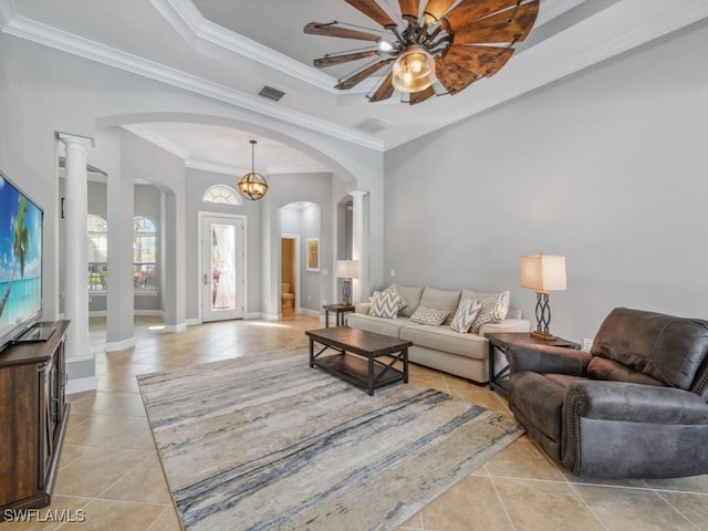 tiled living room featuring ceiling fan with notable chandelier, decorative columns, a raised ceiling, and crown molding