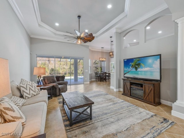 living room featuring a raised ceiling, ceiling fan, decorative columns, and ornamental molding