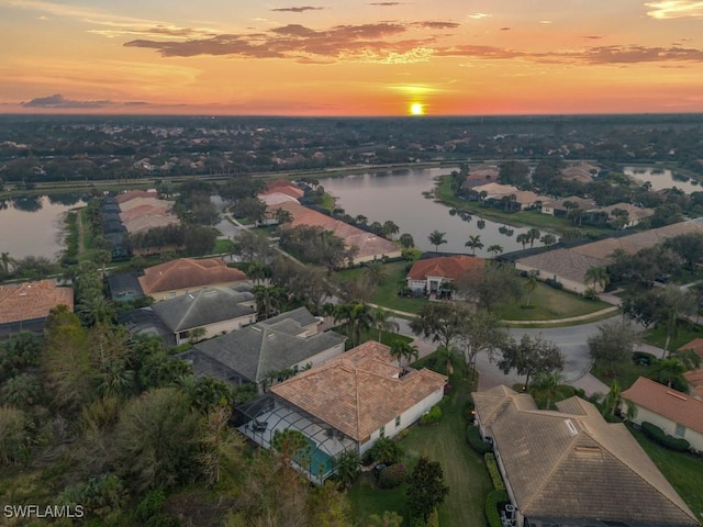 aerial view at dusk featuring a water view