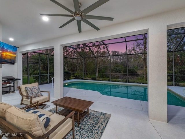 pool at dusk with outdoor lounge area, a patio, glass enclosure, and a grill