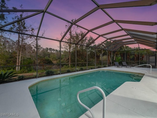 pool at dusk with a patio area and a lanai