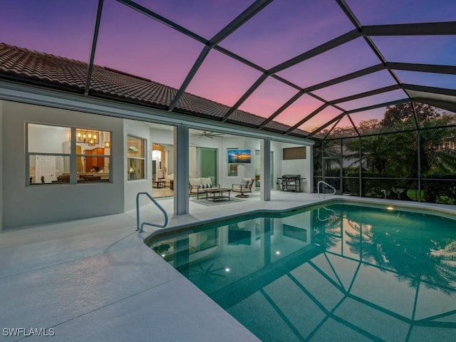 pool at dusk featuring a lanai, an outdoor living space, ceiling fan, and a patio