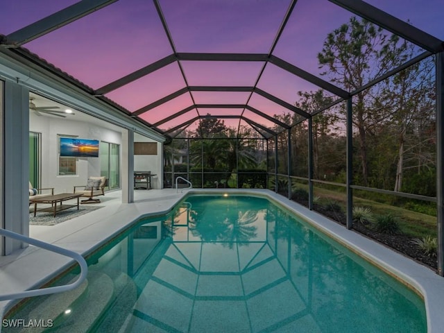 pool at dusk featuring glass enclosure and a patio