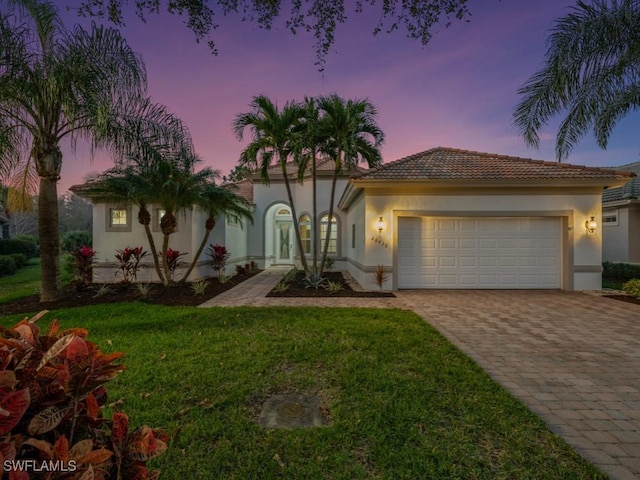 mediterranean / spanish-style home featuring a garage and a yard